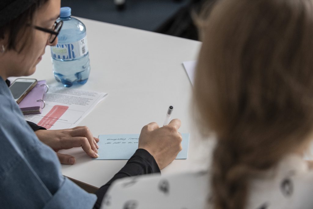 Personen beschreiben eine Moderationskarte